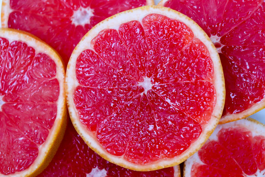 Freshly cut grapefruit slices isolated on a white background, bright pink or red citrus fruit pieces with juicy texture, healthy natural food concept.