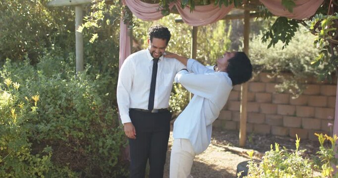 Casual man placing hand on formal man's shoulder, teasing, formal man laughing under pink pergola