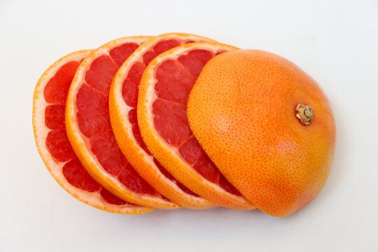 Freshly cut grapefruit slices isolated on a white background, bright pink or red citrus fruit pieces with juicy texture, healthy natural food concept.