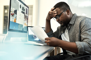Fototapeta premium Computer screen, documents and stress with web designer black man in office for problem solving. Paperwork, pc and reading with African developer at desk in creative workplace for planning mistake