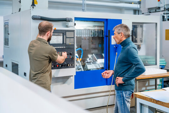 Engineer explaining machine system to operator in production hall