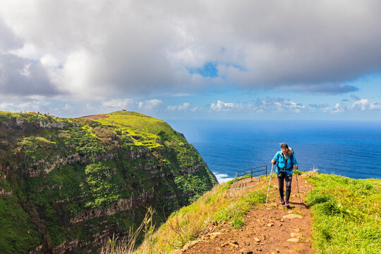 Hiker with backpack walking on scenic trail by coastal cliffs Madeira