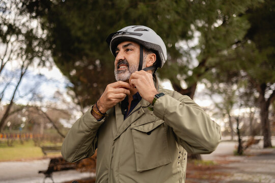 Man fastening helmet outdoors in a park on a sunny day