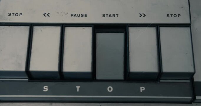 Pushing the start button of a vintage tape recorder in dim light