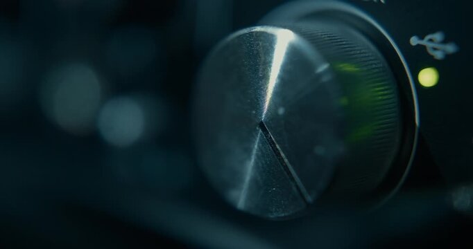 Close-up detail of a hand turning up the volume of a recording device