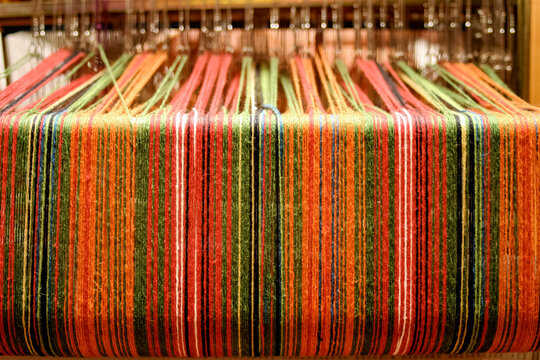 Colorful Woven Textile on Loom with Striped Thread Pattern Background