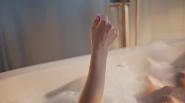 Spa lady washing hands lying luxury bath covered fluffy bubbles chilling closeup