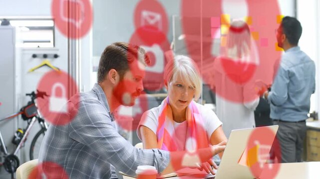 Bearded man pointing at laptop, woman typing finalizing plan in business office, red icons shifting