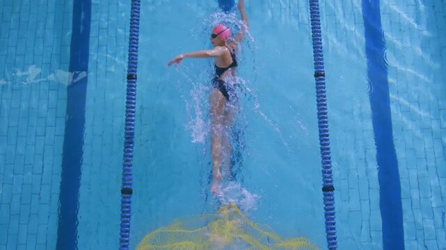 Swimmer backstroking down lane passing center causing yellow plume and forming wake showing flow