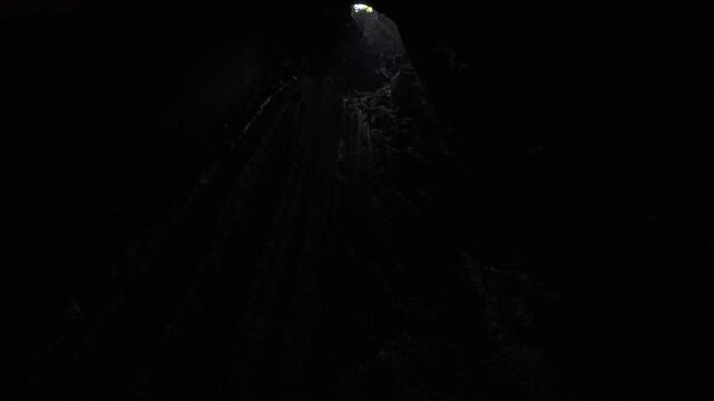 From the bottom of a pitch black cave in limestone looking up towards the light at the entrance 90 metres above at Tham Pong, Laos.