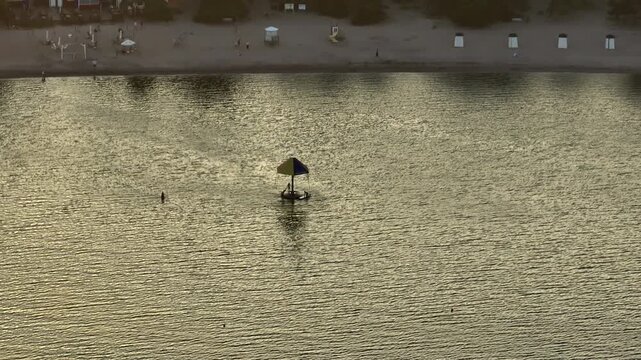 Telephoto drone shot around summer bathers and water carousel at Plagen, Finland