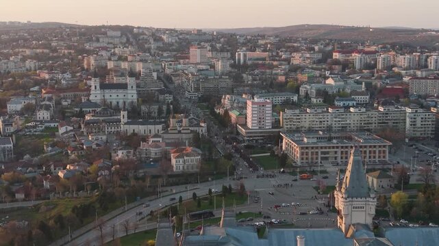 Aerial view over Iași city center in Romania during sunset, showcasing historic buildings, churches, and busy streets. Warm golden light highlights the urban landscape and architectural mix of the cit