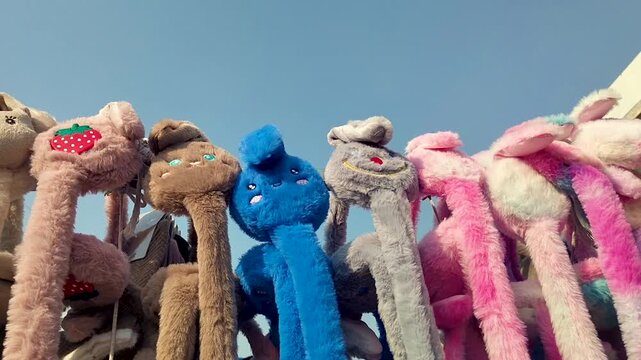 Colorful fluffy ear muffs displayed at local street market stall, showcasing vibrant and fun designs. Perfect for winter fashion, accessories, and street shopping footage.