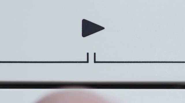 White play button with black triangle symbol being pressed in macro close up