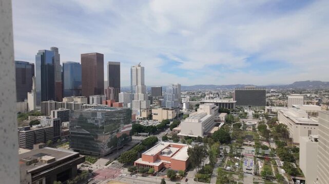 Gimbal panning and racking focus shot of the downtown skyline and Grand Park from the observation deck at City Hall in Los Angeles, California. 4K