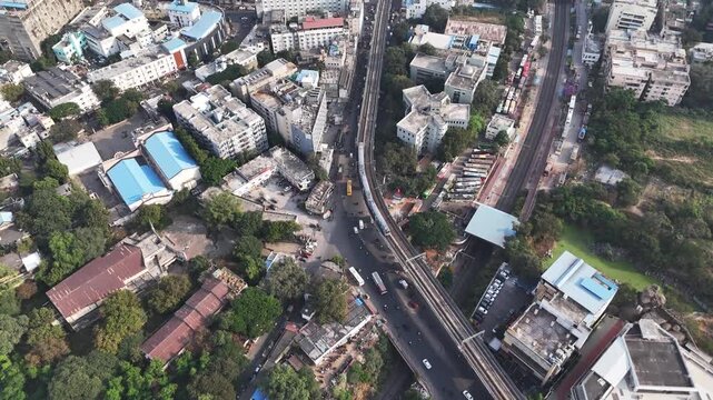Aerial view of Hyderabad featuring an elevated metro line running through dense residential and commercial buildings, highlighting modern urban transport. Bus station parallel