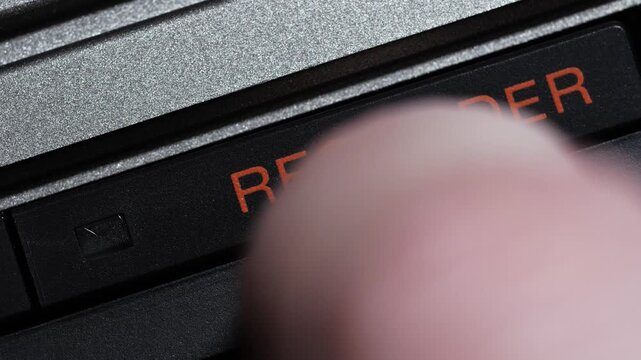 Finger pressing black recorder button with orange text on vintage controller