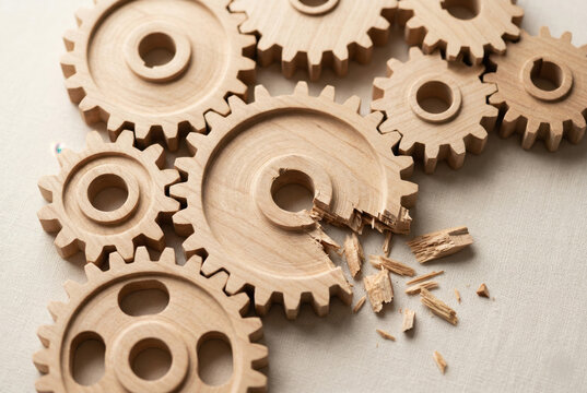 Interlocked wooden gears with missing teeth showing operational failure