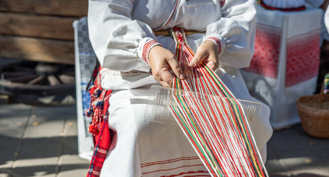 Process of weaving. Hands of a woman as they carefully manipulate colorful threads on a loom. Traditional clothing adds a touch of cultural significance, suggesting a connection to artisan skills.
