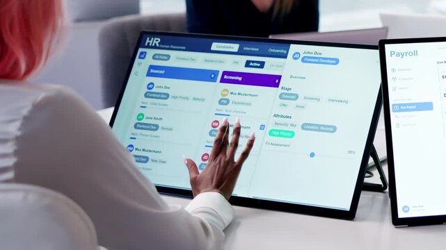 HR Manager Reviews Payroll Software On Tablet During Team Meeting