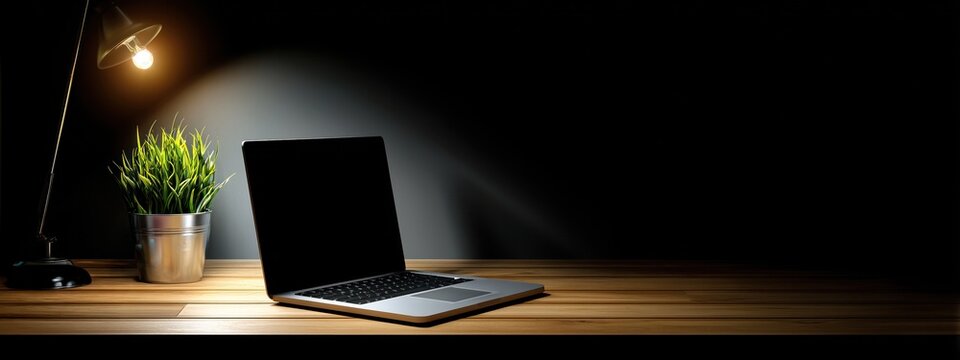 Bureau &agrave; domicile, la nuit avec un ordinateur portable &eacute;clair&eacute; par une lampe de bureau, ambiance sombre et minimaliste, vue panoramique