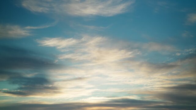The calm movement of fluffy white clouds across the blue sky at sunset. Heavenly timelapse, calm, windless weather.