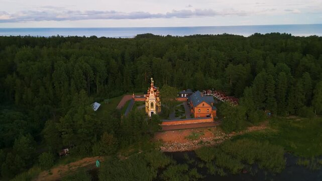 Epic Ladoga lake monastery aerial orbit. 
Cinematic 4K drone panorama of historic 
orthodox Christian skete and isolated 
forest coastline on Konevets island, Russia.
