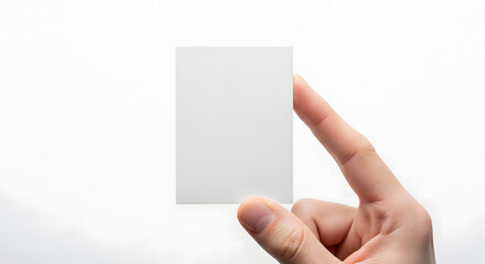 Obraz premium A single human hand holds a vertical blank white rectangular paper card, providing a perfect clean template for custom designs.