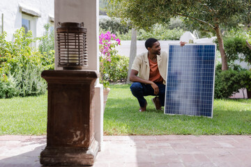 Man crouching on lawn adjusting solar panel while sunlight activating animated chart over panel © wavebreak3