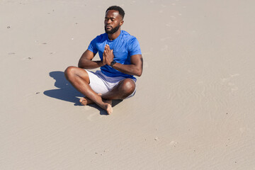 Mid-adult man meditating on sand, watch vibrating and sending animated breath rings for wellness © wavebreak3