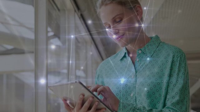 Female professional tapping tablet, causing network overlay to brighten and visualizing tech data