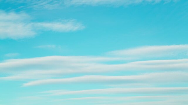 The calm movement of fluffy white clouds across the blue sky. Heavenly timelapse, calm, windless weather.