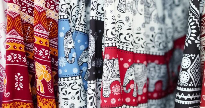 Colorful elephant patterned fabrics hanging in row, showcasing Asian textile design, Hawaii shirt, cultural fashion, Thai traditional patterns, and vibrant clothing industry background