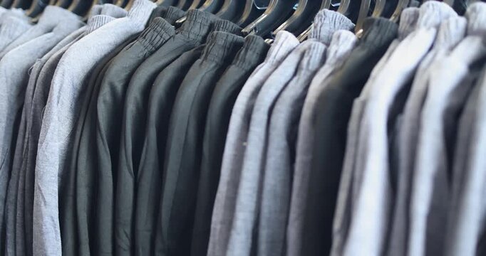 Gray and black pants neatly hanging on a rack in store. Minimal and elegant style, perfect for casual outfits and modern business wear