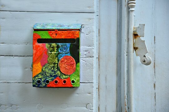 Colorful hand painted mail box on a weathered light blue wooden door in the picturesque village of Ansouis in Provence-Alpes-C&ocirc;te d'Azur, France.