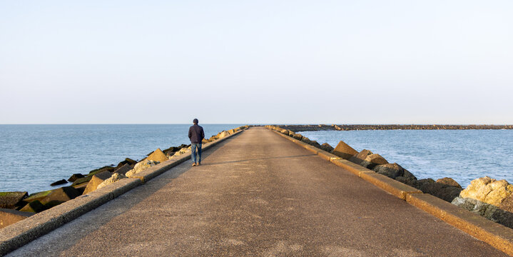 Person having an early morning stroll on the IJmuiden pier in the North Sea (Netherlands) on a sunny but cold winter morning