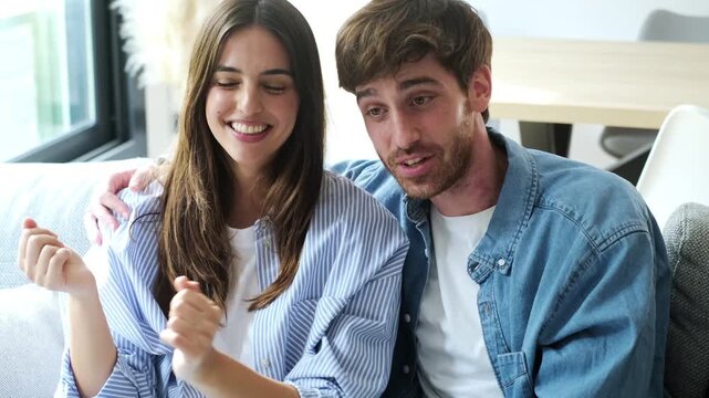 A Happy Young Couple Waves at the Camera While Enjoying a Video Call From Their Modern Home