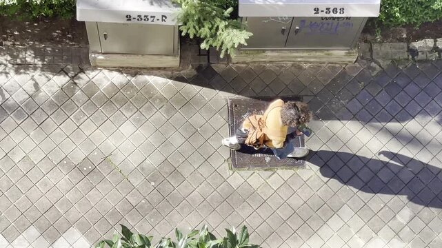 Chico joven hablando por tel&eacute;fono m&oacute;vil y caminando a vista de dron con sombra alargada y silueta