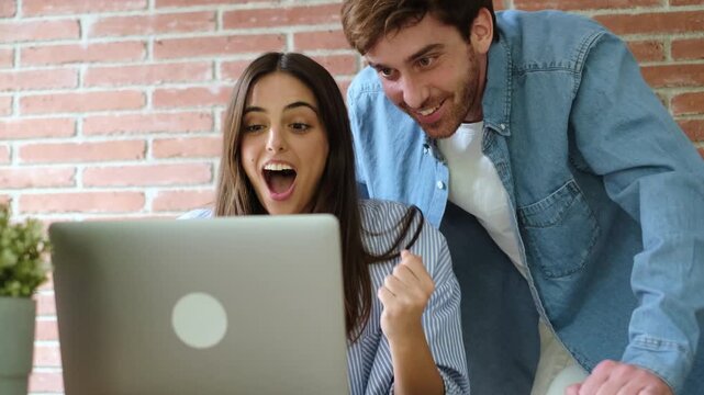 Excited Young Couple Celebrating Success While Looking at a Laptop Screen Together