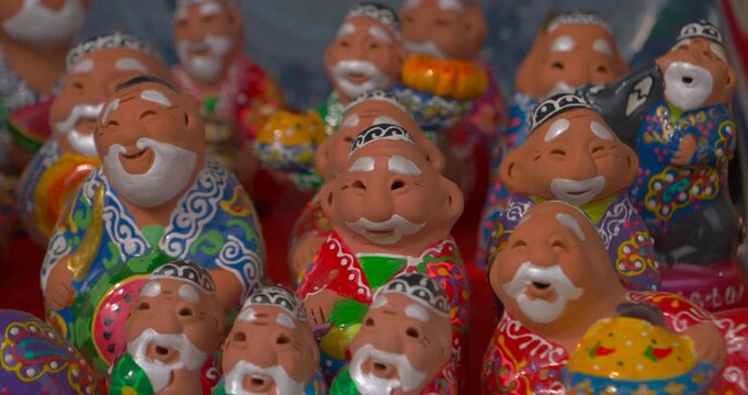 Close up video of colorful handmade clay figurines of smiling old men in traditional robes bright folk souvenirs decorative craft and cultural gift concept playful folk style and handcrafted