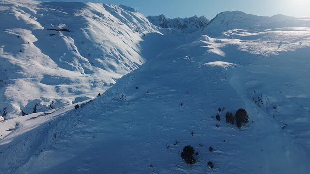 Drone rises along ridge revealing snowy valley at Font Frede in Pyrenees France