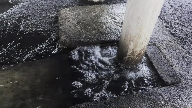 Clogged drainage system overflowing with dirty water on a city street.