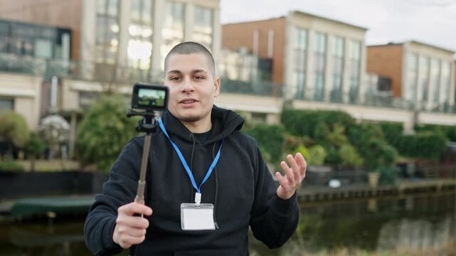 Young male blogger vlogging with an action camera on a selfie stick outdoors, sharing content on social media