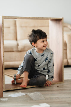 Smiling child playing inside furniture piece at home during assembly