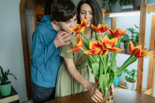 Smiling mother and son giving fresh tulip bouquet at home