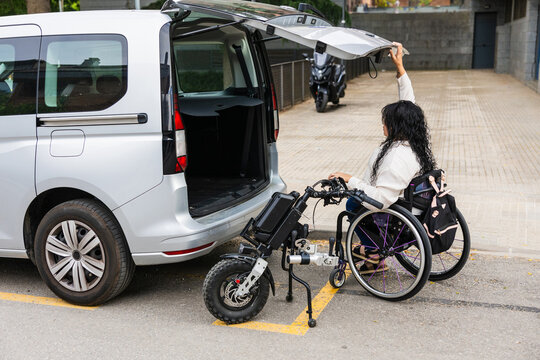 Wheelchair user with electric handbike opening trunk of accessible van