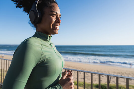 Athlete running with headphones along beachside in morning sunlight