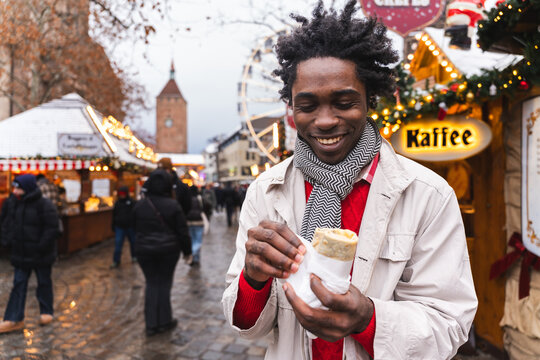 Man eating street food at festive Christmas market outdoors