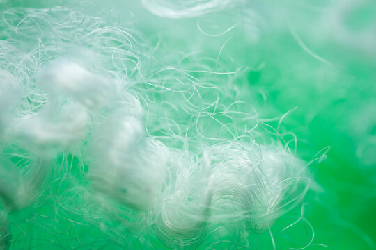 Extreme macro of polyester stable fiber on green background. Selective focus, shallow depth of field. Abstract dreamy background