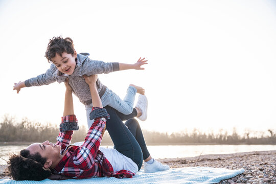 Mother and son playing together outdoors by riverside on beach